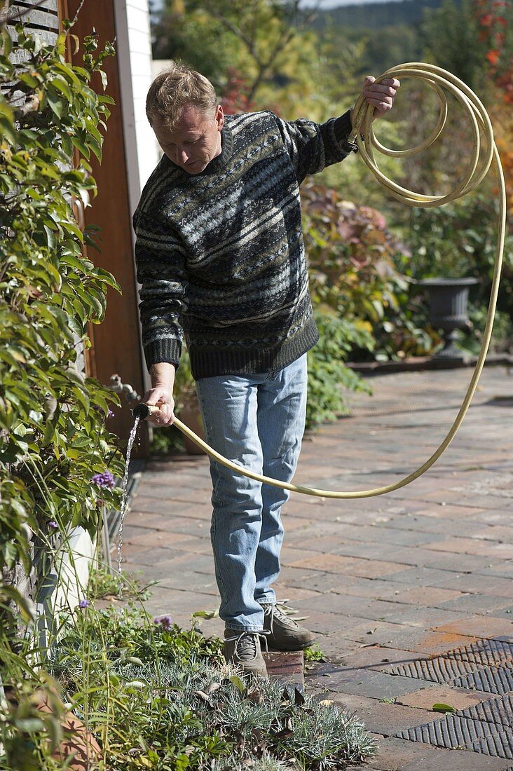 Man emptying garden hose before winter storage
