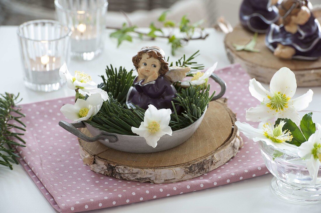 Christmas table decoration: Angel in a small bowl with Helleborus flowers