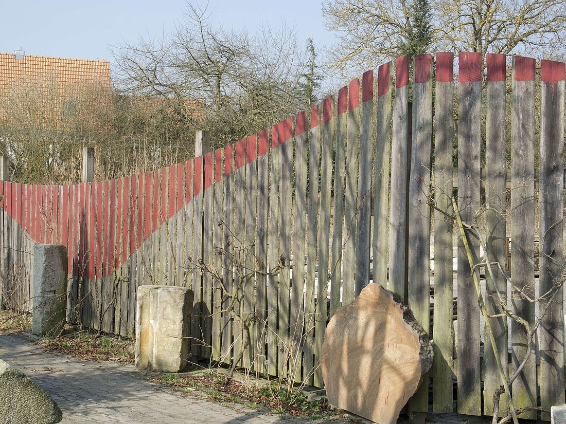 Wooden garden fence decorated with red paint