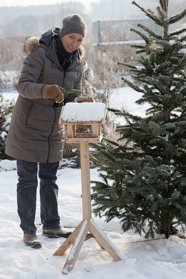 Woman filling bird house with sunflower seeds