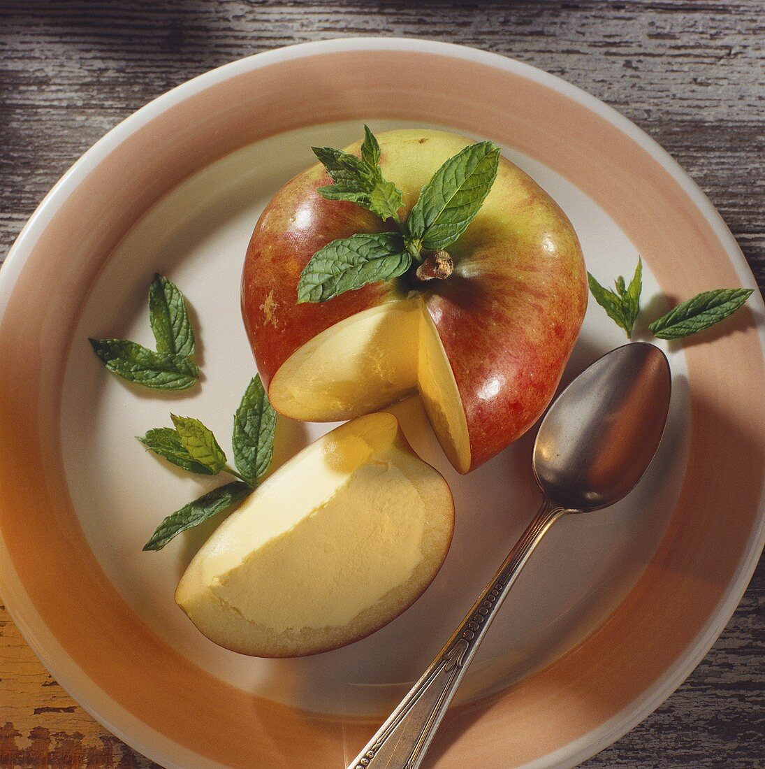 Apfel mit Vanilleeis gefüllt auf Teller, Deko: Minzblättchen