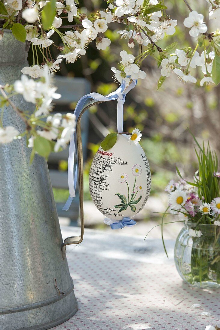 Hand-painted Easter egg on Prunus bouquet in zinc pot