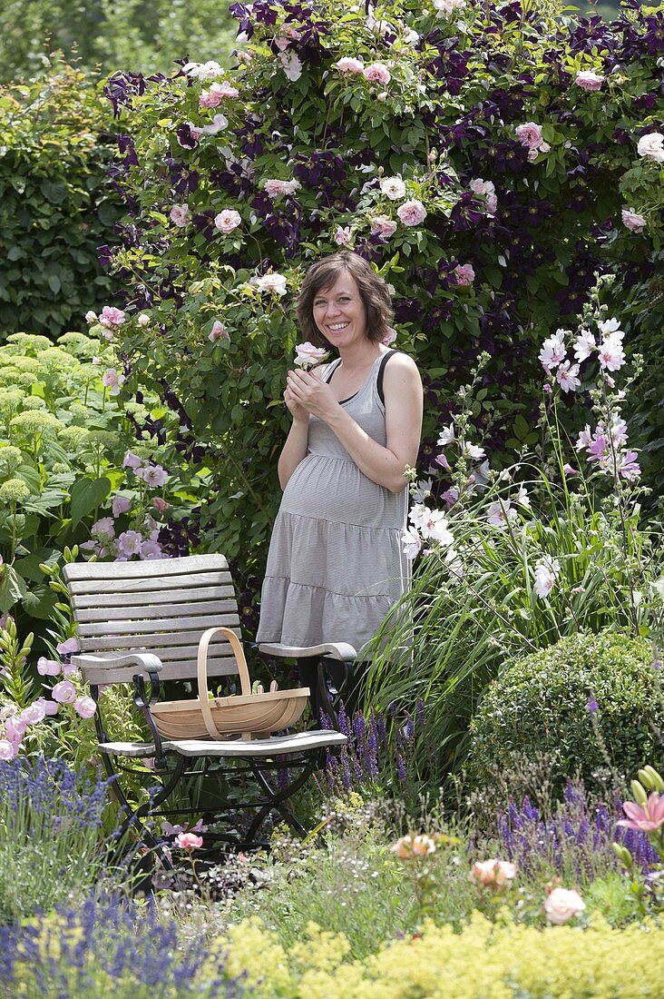 Pregnant woman enjoying the scent in the rose garden