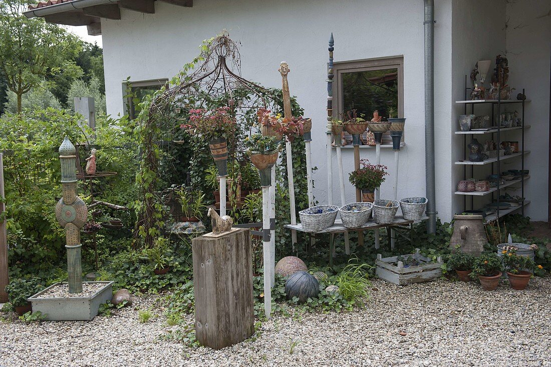 Kies-Terrasse mit getöpferten Dekoelementen und Säule als Wasserspiel