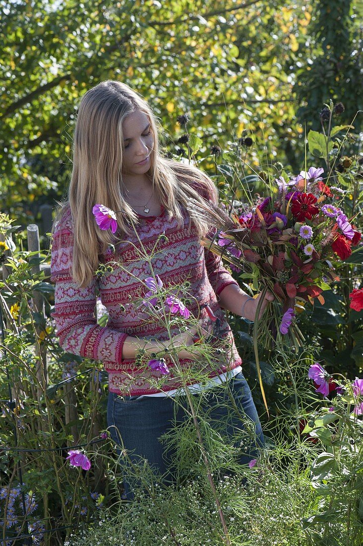 Young woman cutting the last summer flowers in the cottage garden