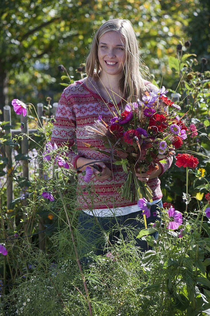 Young woman cutting the last summer flowers in the cottage garden