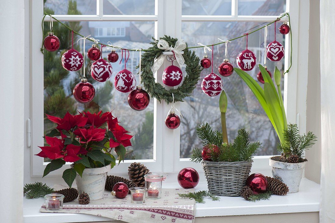 Weihnachtliche Fensterdeko mit roten Glaskugeln und rot-weissen gestrickten Kugeln