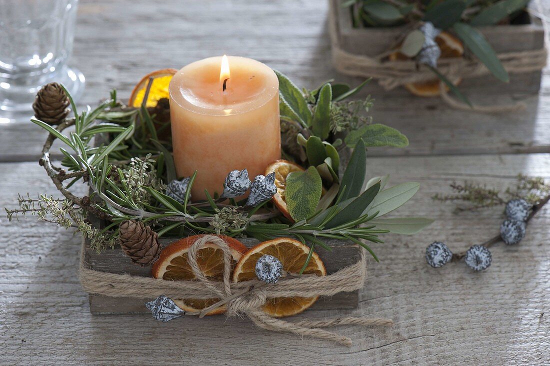 Candle with mediterranean herbs in wooden box