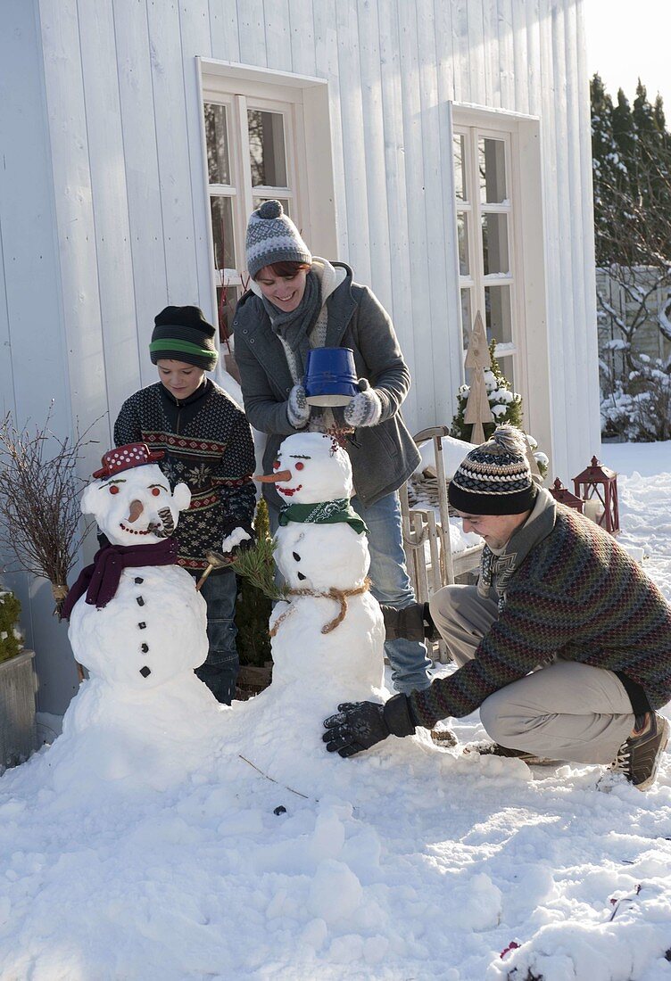 Family building snowman on terrace