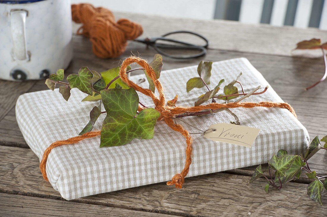 Gift book wrapped in tea towel with orange cord and tendril