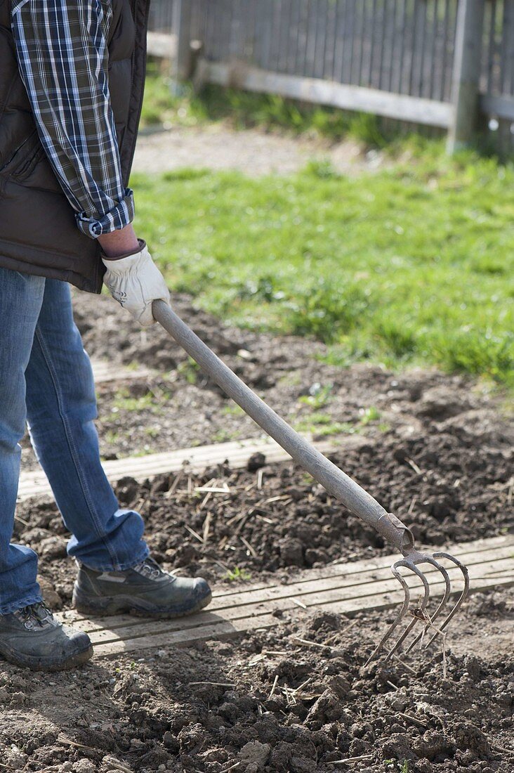 Man loosening soil with a wedge