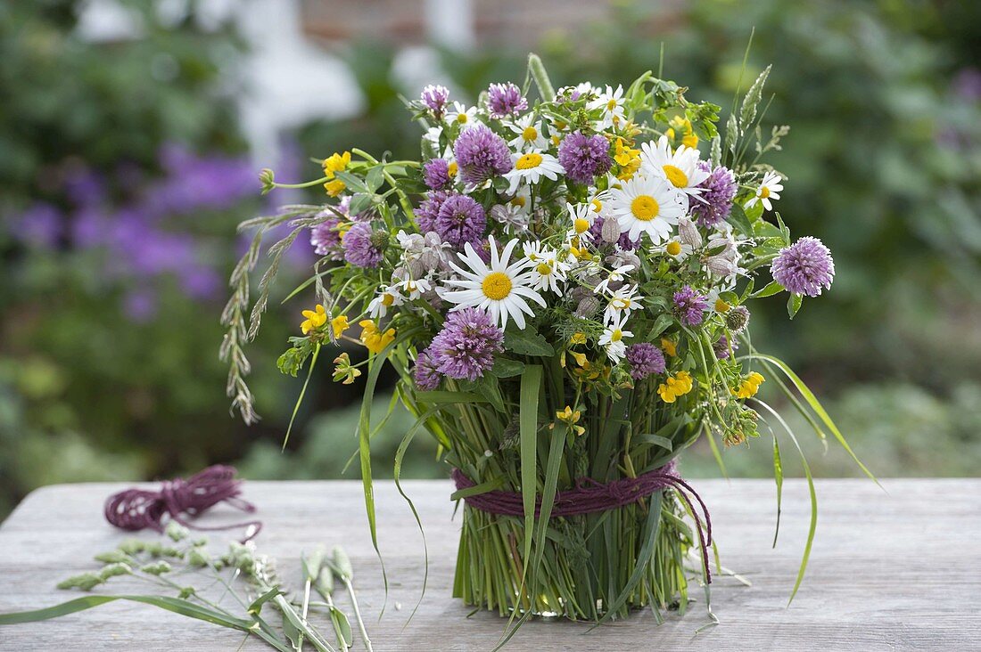 Bunter Wiesenstrauss in mit Gras verkleideter Vase