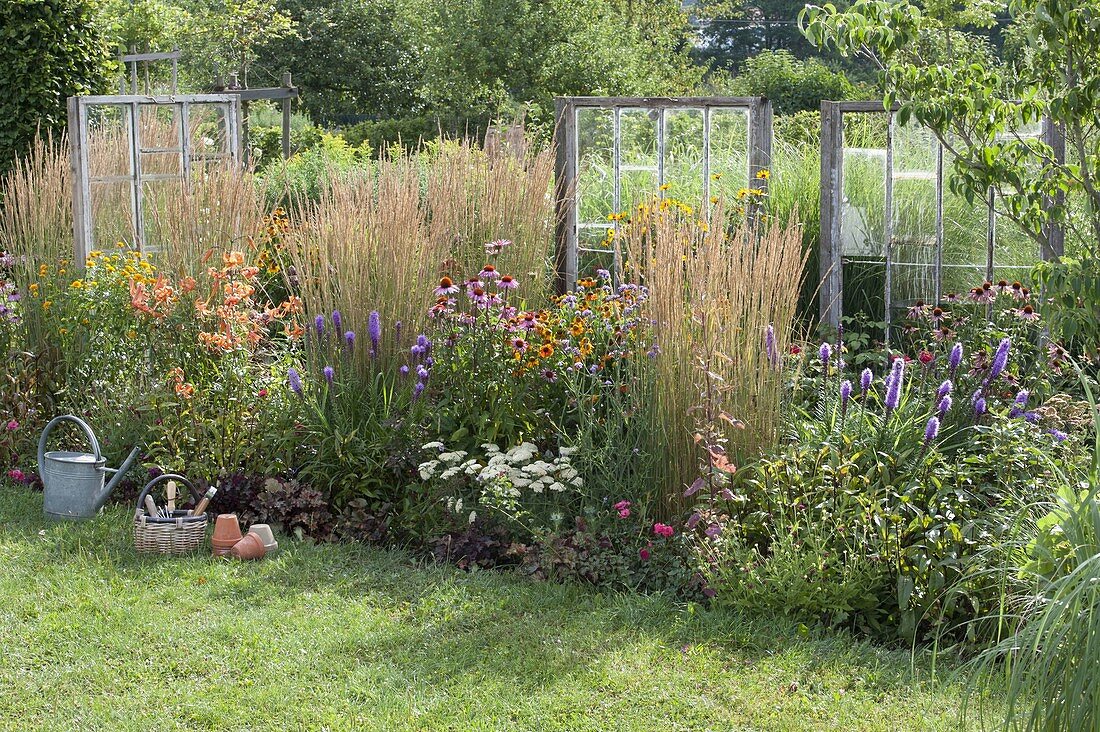 Perennial border with old windows as decorative objects