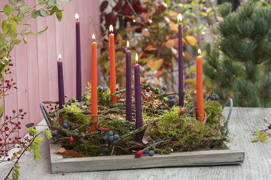 Wreath made of natural materials with candles on wooden tray