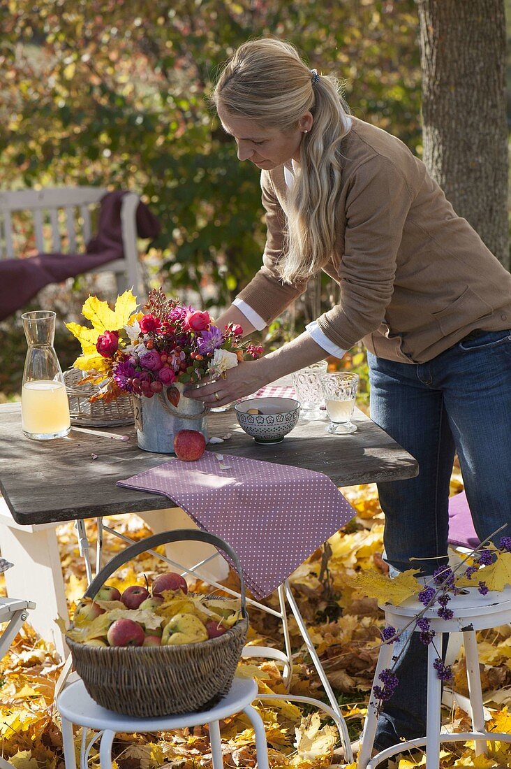 Family at table in golden autumn leaves under maple tree