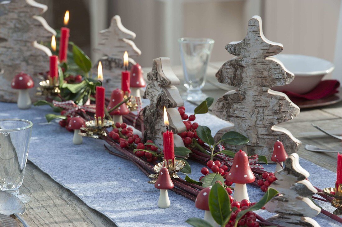 Table laid with small Christmas trees made of birch bark, red berries