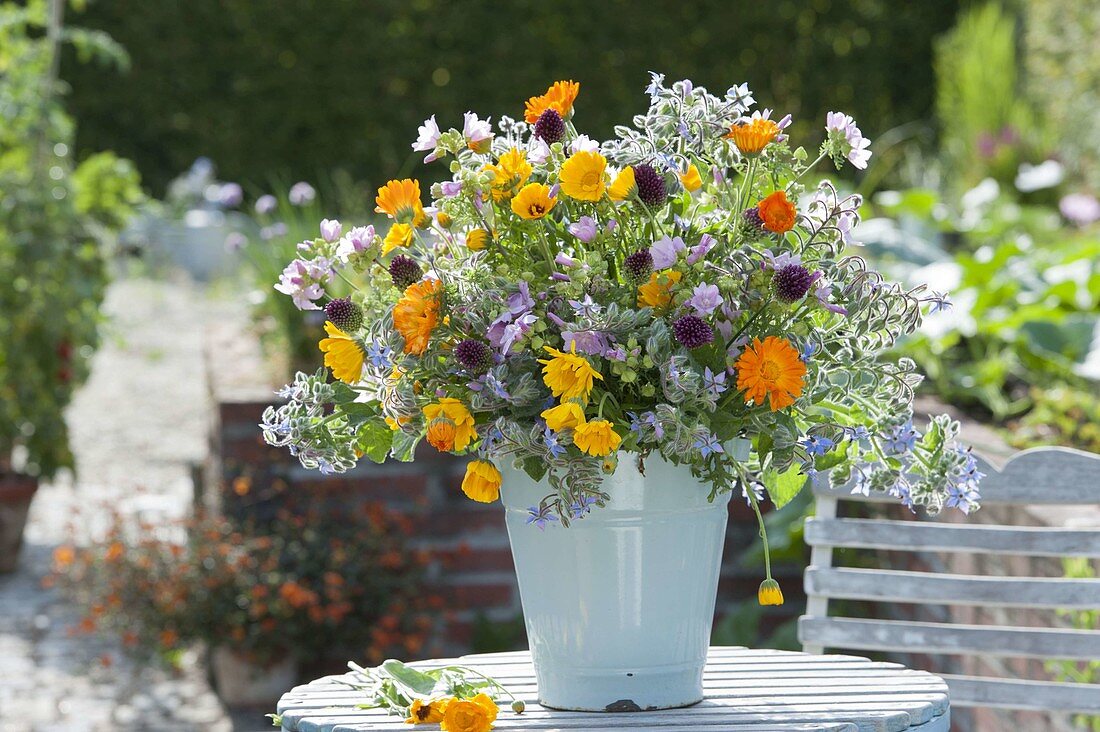 Lush bouquet of herbs in the enamel bucket on the garden table