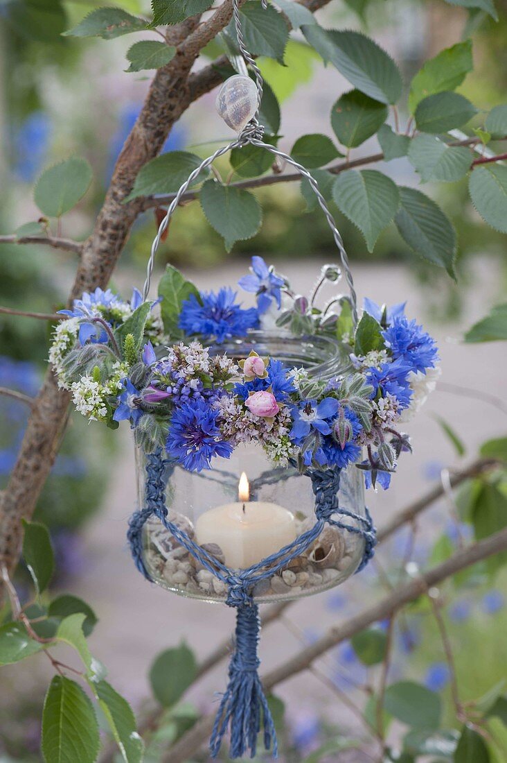 Preserving jar with macrame as lantern on tree, small summer wreath