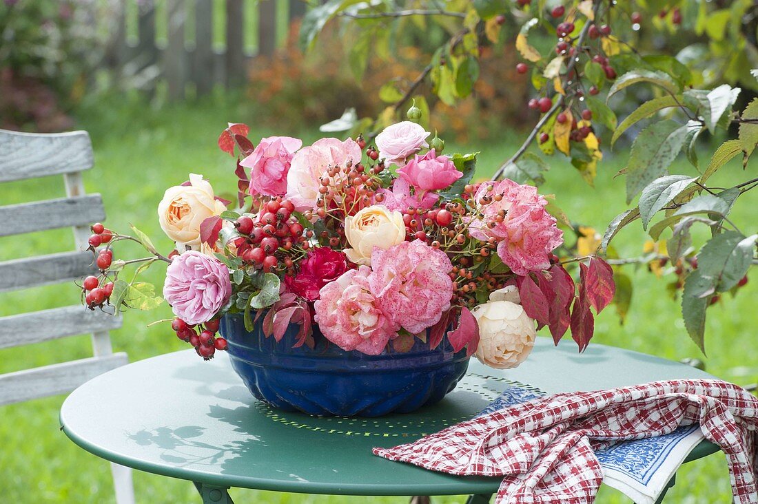 Arrangement in old cake form with rose (rosehips) on garden table