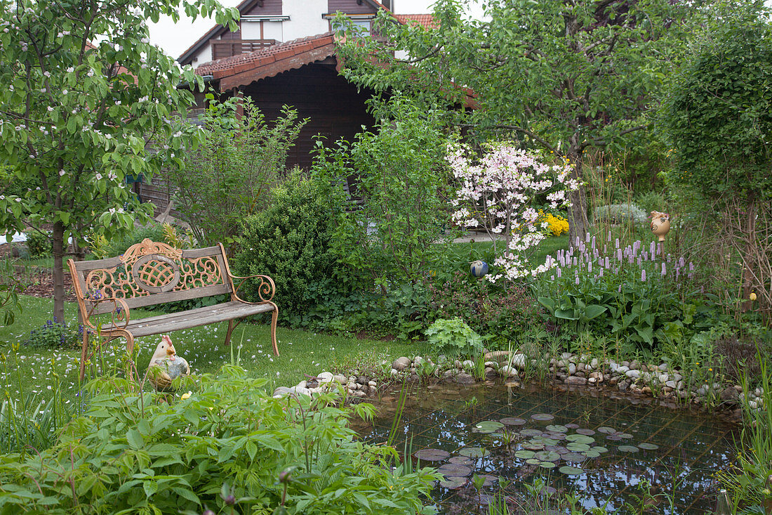 Romantic spring garden with bench at the pond
