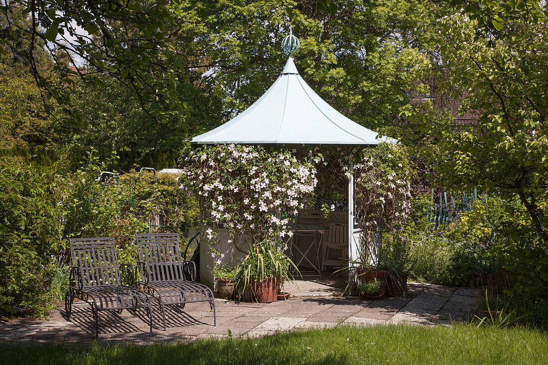 Runder Pavillon berankt mit Clematis montana (Berg-Waldrebe), Liegen auf kleiner Terrasse