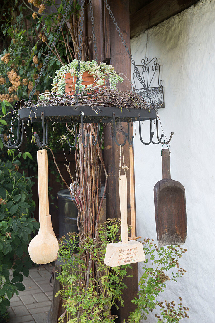 Misused drying rack for herbs with wooden flour scoop, meat tenderiser and ladle, wreath of twigs and pot with Sedum morganianum (snake stonecrop)