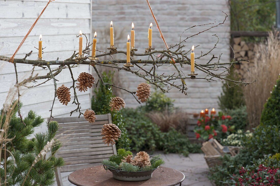 Hanging branch with pine cones and candles over patio table