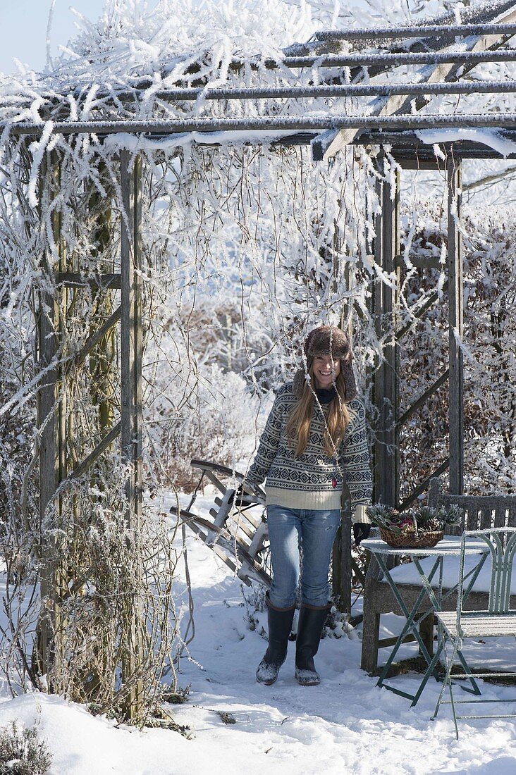 Wooden pavilion with hoarfrost covered in snowy garden