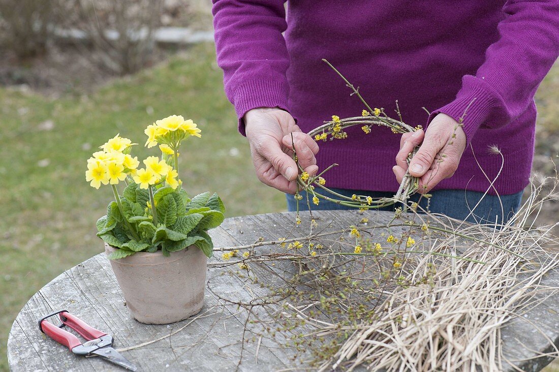 Easter table decoration with wreath of twigs, grasses and yellow primrose