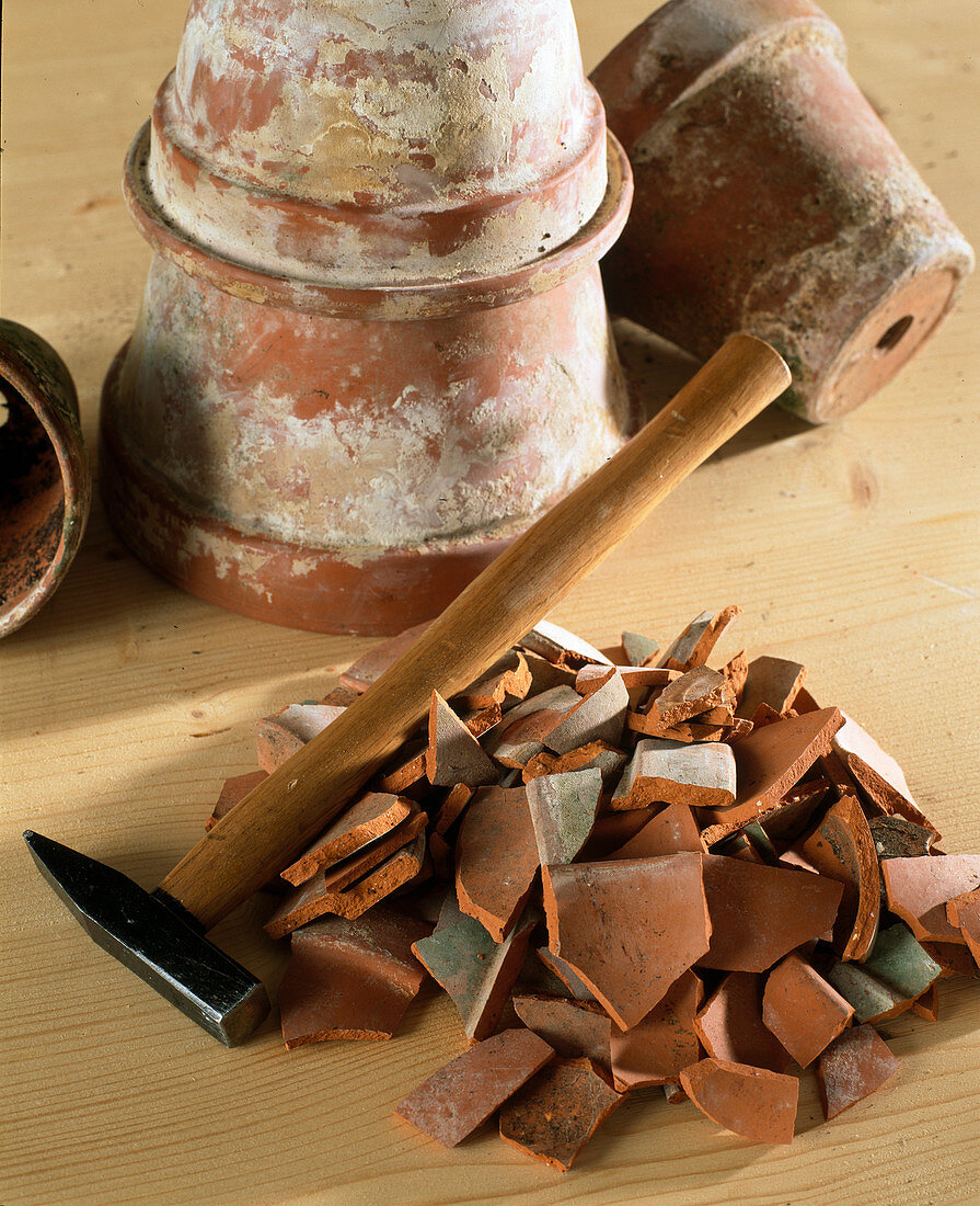 Crushing old clay pots with a hammer