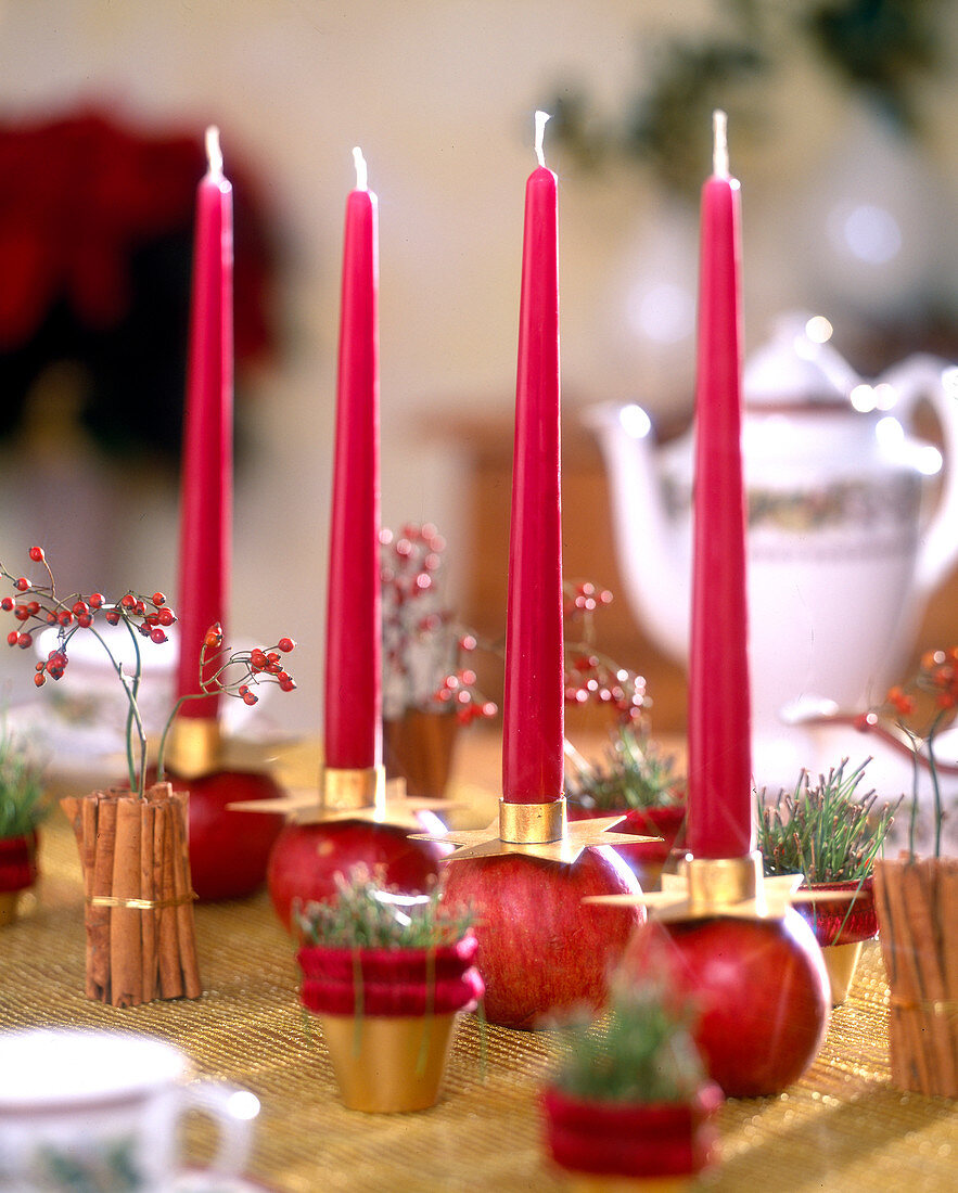 Christmas decorated table with red candles on apples, rosehips in cinnamon