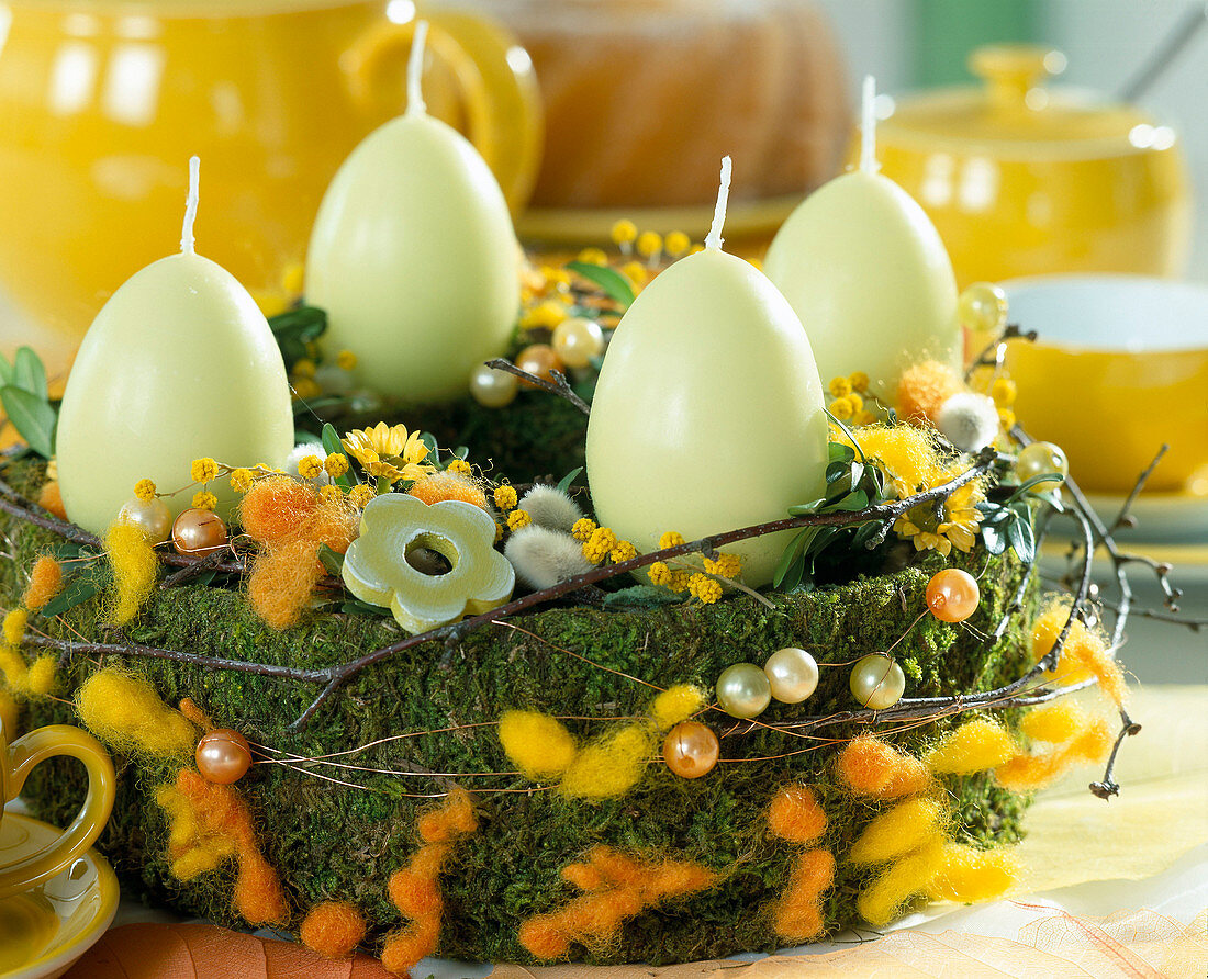 Easter wreath made of moss, coloured cotton wool, beads and dry twigs