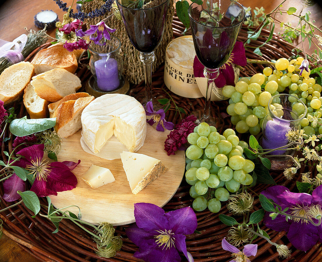 Stil mit Käse, Baguette, Weintrauben, Clematisblüten