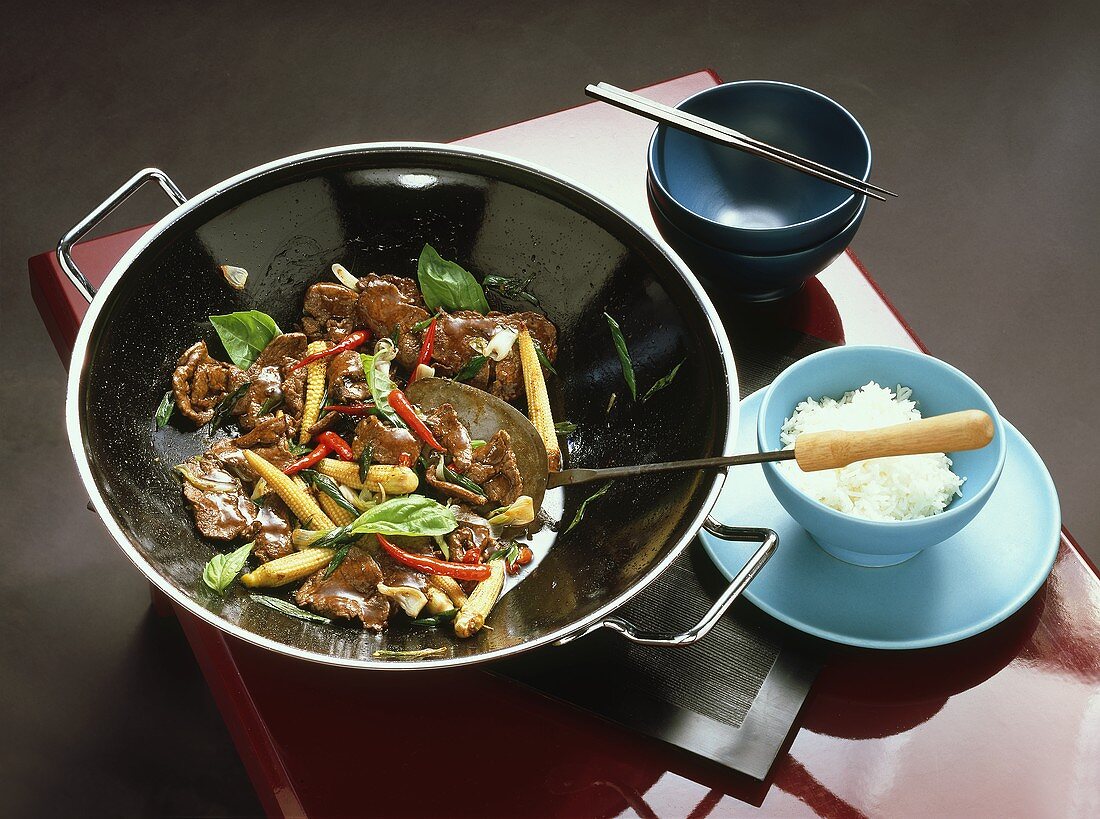 Beef with sweetcorn in wok and a small bowl of rice