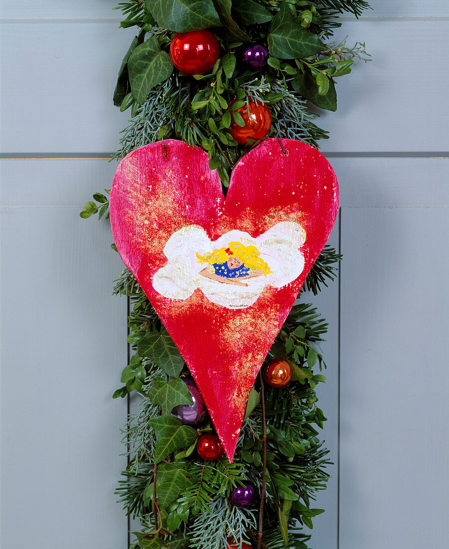 Door decoration as garland of twigs and red wooden heart