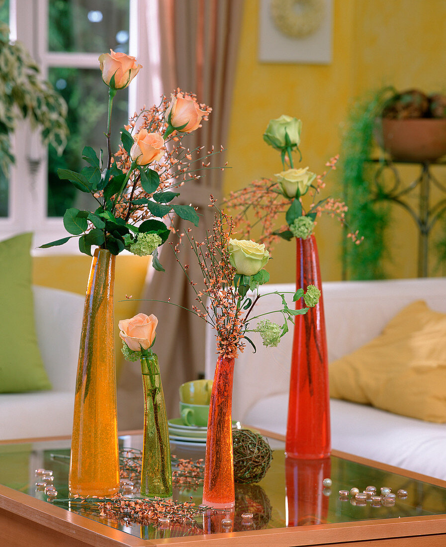 Rose blossoms in long coloured glass vases, salmon coloured