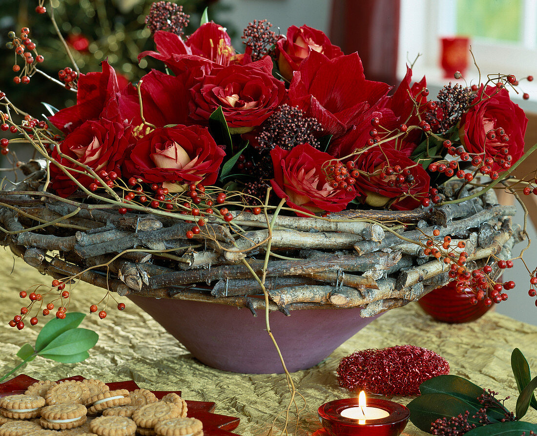 Bowl with wreath of canes, red roses, rosehip twigs, skimmia (skimmia)