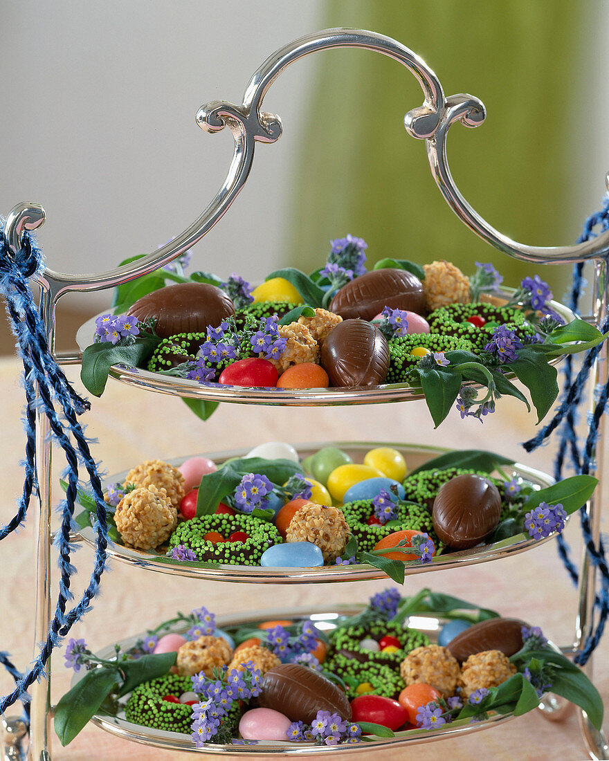 Silver tagere with chocolate eggs and myosotis (forget-me-not flowers)