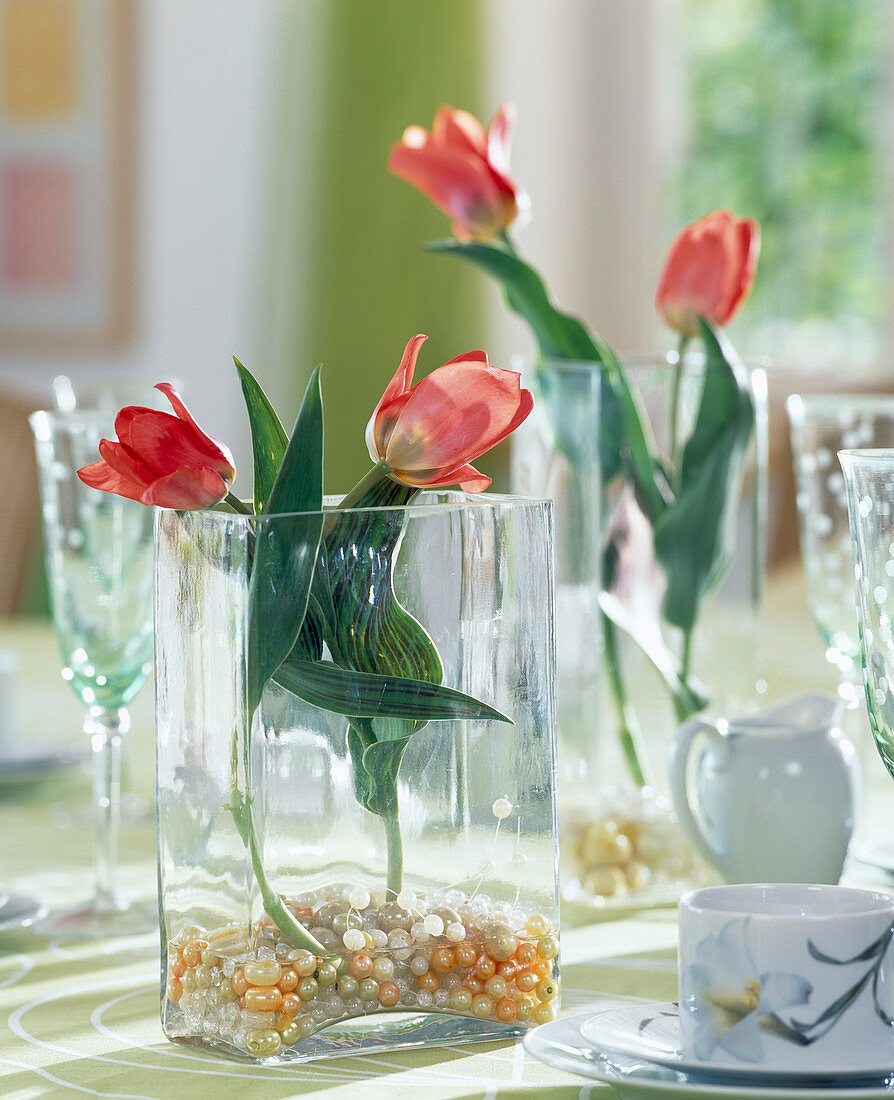 Glasgefäß mit Kugeln und Tulpen