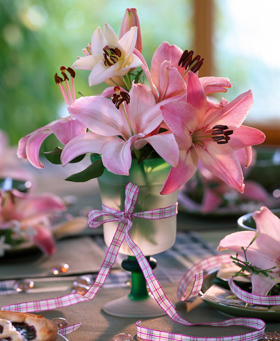 Lilium asiaticum 'Vermeer' (lilies) in wine glass, red and white ribbon