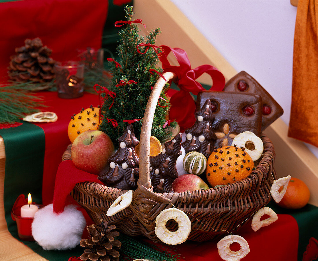 Christmas gift basket with gingerbread, chocolate fir trees, clove oranges