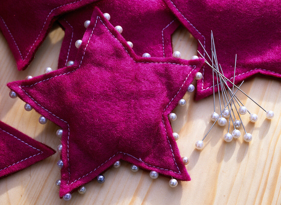 Cyclamen-coloured felt star sewn and trimmed with decorative pins