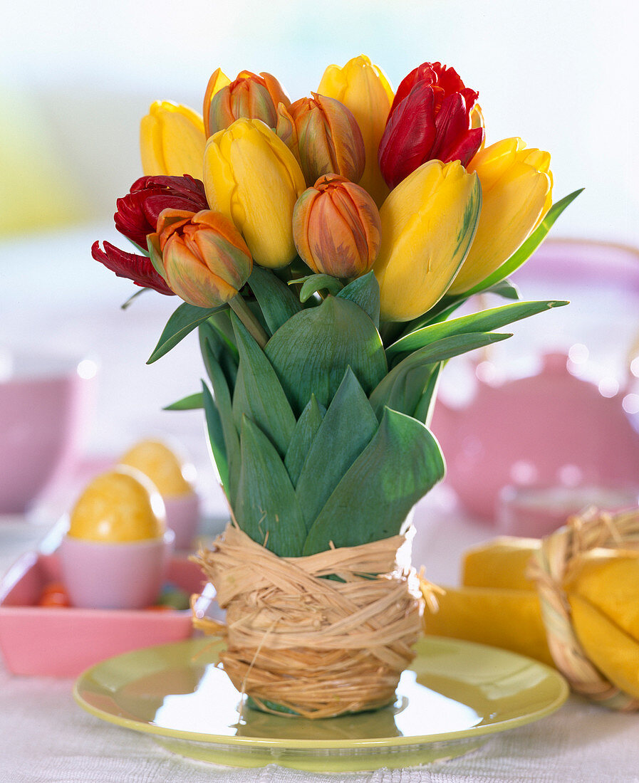 Tulipa (yellow, orange, red tulips), vase wrapped with raffia