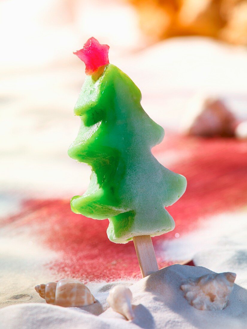 A tree-shaped ice lolly on a sandy beach
