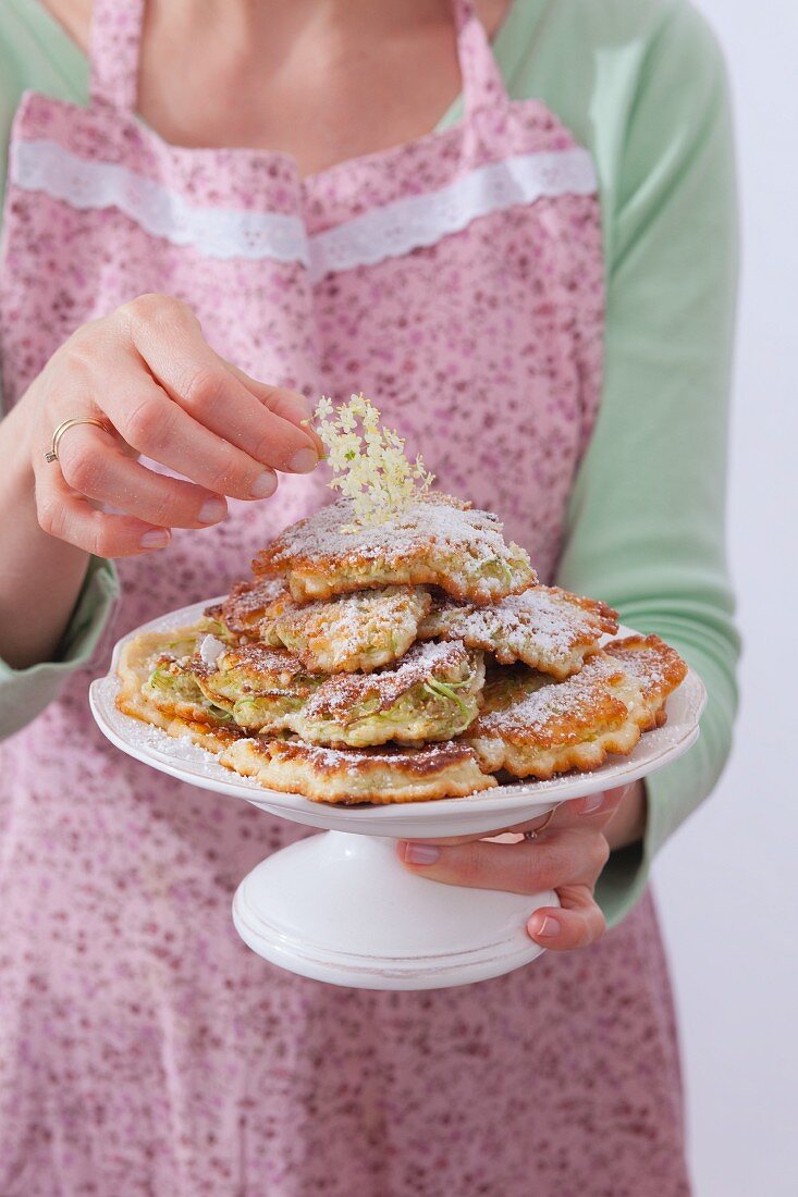 Frau serviert Pancakes mit Holunderblüten
