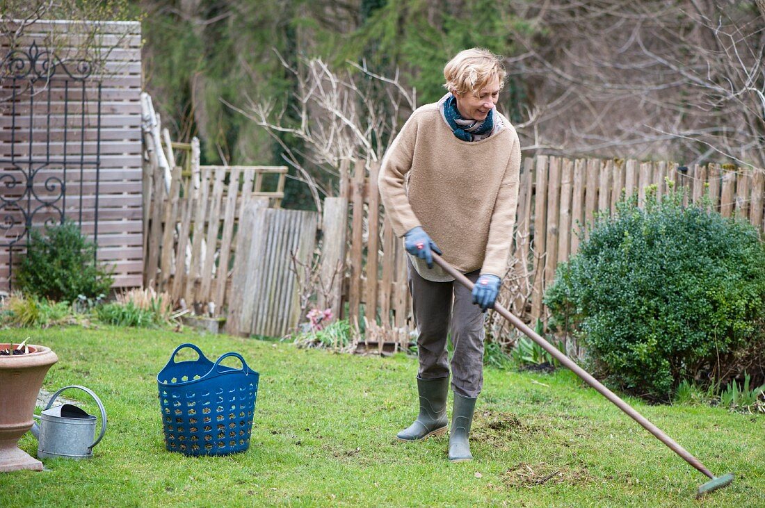 Woman raking thatch from lawn