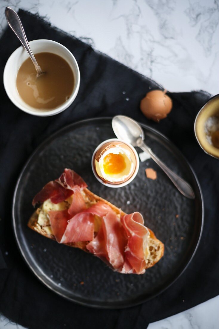 Breakfast with a soft-boiled egg and bread with ham
