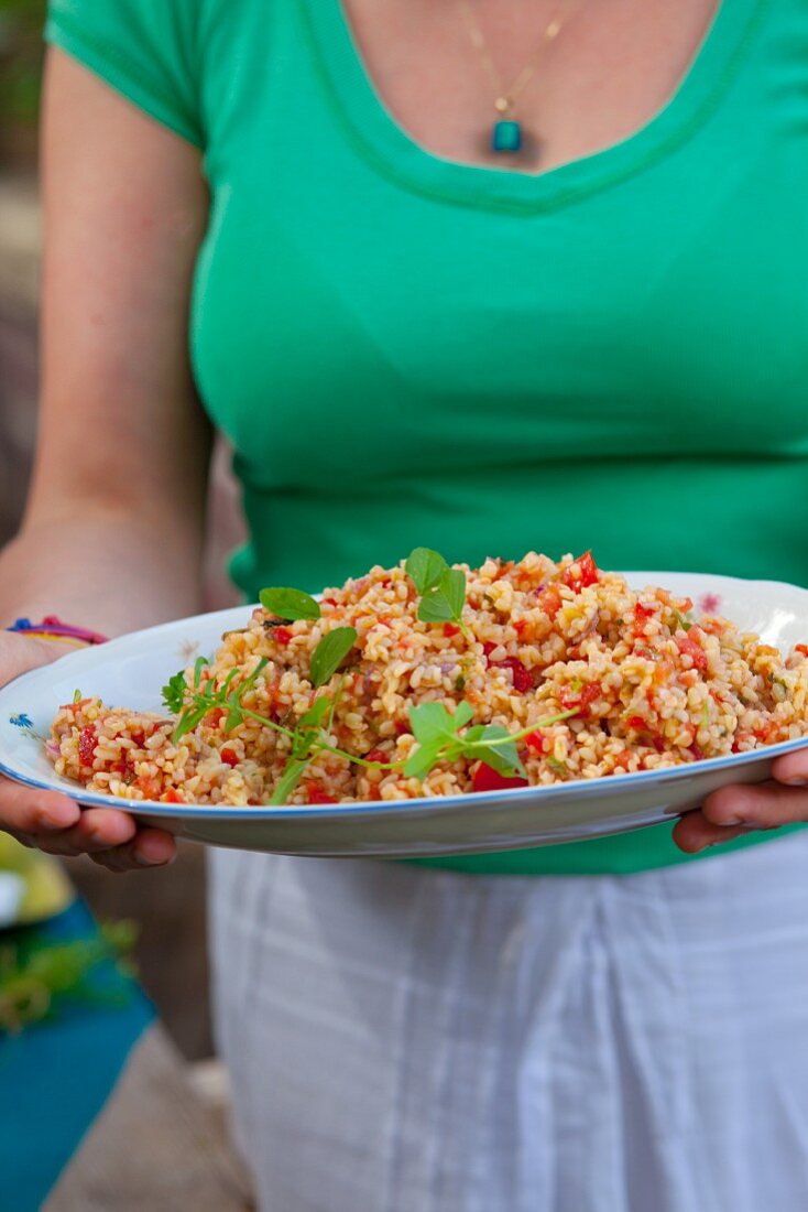 Frau serviert Graupen-Tomaten-Salat