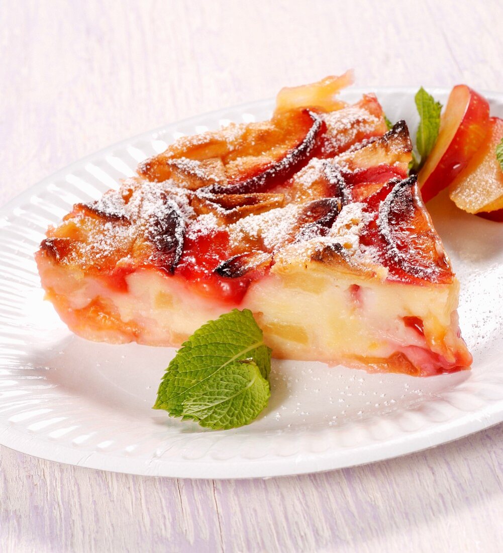 A slice of fruit tart with icing sugar and mint