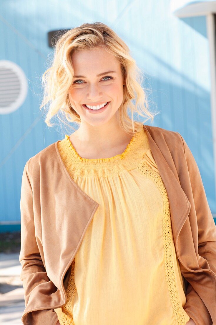 Blonde woman wearing yellow top and brown velour cardigan